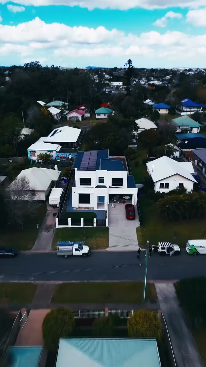 Aerial view of a two-storey white Brisbane house with a rooftop solar array.