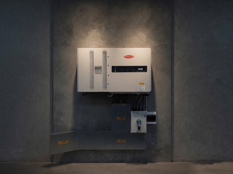 A commercial solar inverter and isolation equipment mounted on a finished plant room wall.