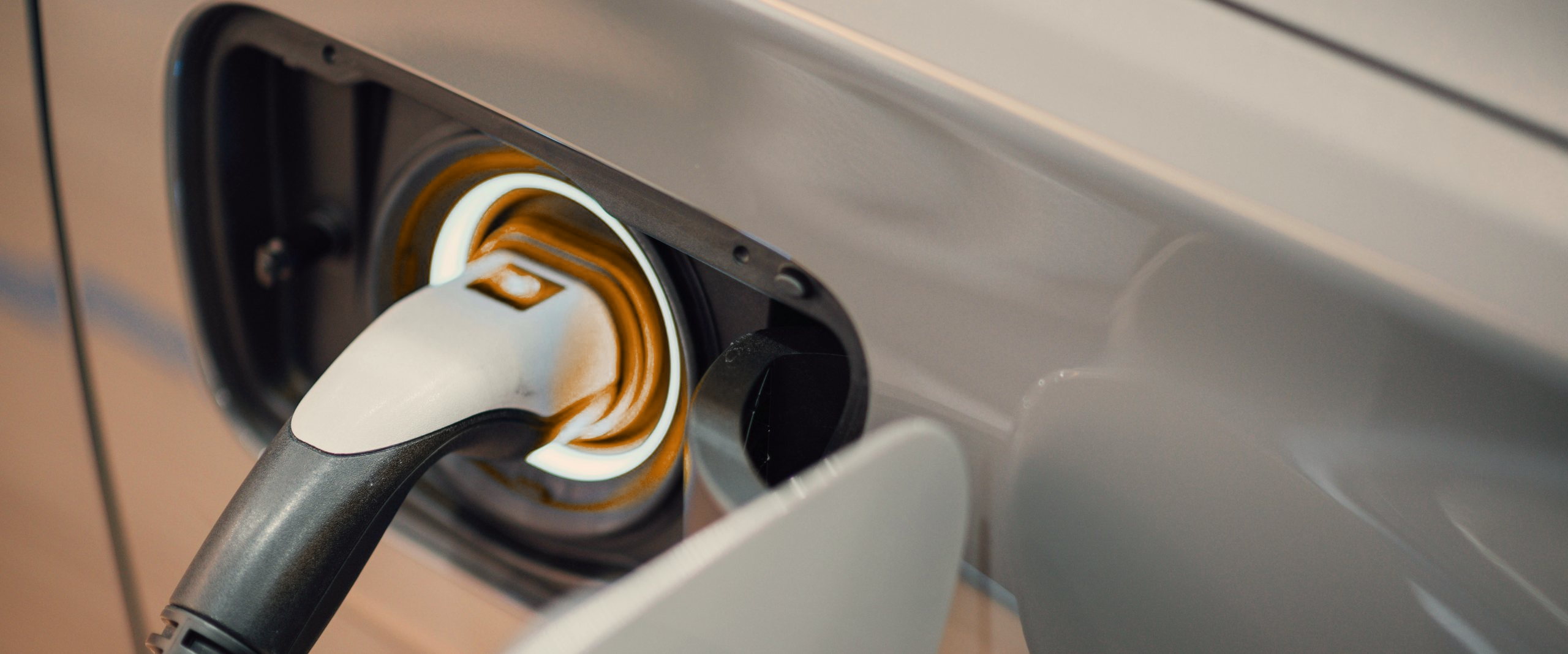 A charging connector plugged into the charge port of an electric car.